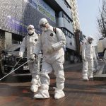 Petugas dengan pakaian pelindung menyemprotkan disinfektan di kawasan kota Daegu, Korsel (Kim Jun-beom/Yonhap via AP)