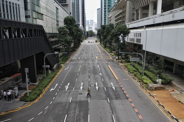 Seorang wanita melintasi jalan kosong di luar Shenton House, Singapura, 7 April 2020. Foto/Straits Times/ Joel Chan