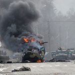 Foto ini menunjukkan sebuah kendaraan pengangkut personel lapis baja Rusia (APC) terbakar di samping tubuh tentara tak dikenal selama pertempuran dengan angkatan bersenjata Ukraina di Kharkiv, Ukraina, Minggu (27/2/2022). [Sergey BOBOK / AFP]